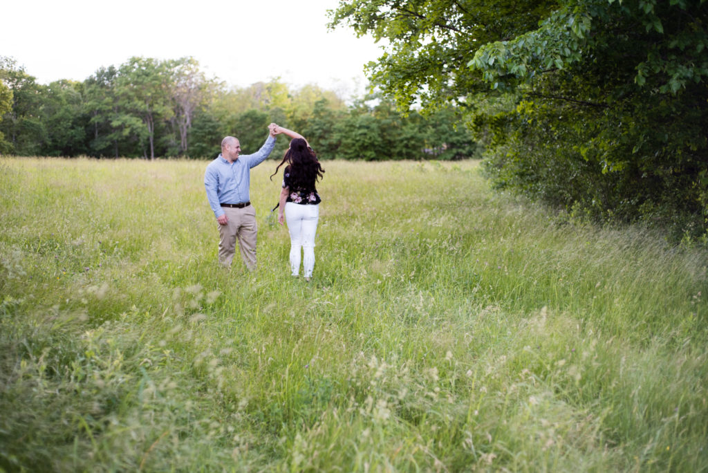couple dancing and twirling in a field at sunset