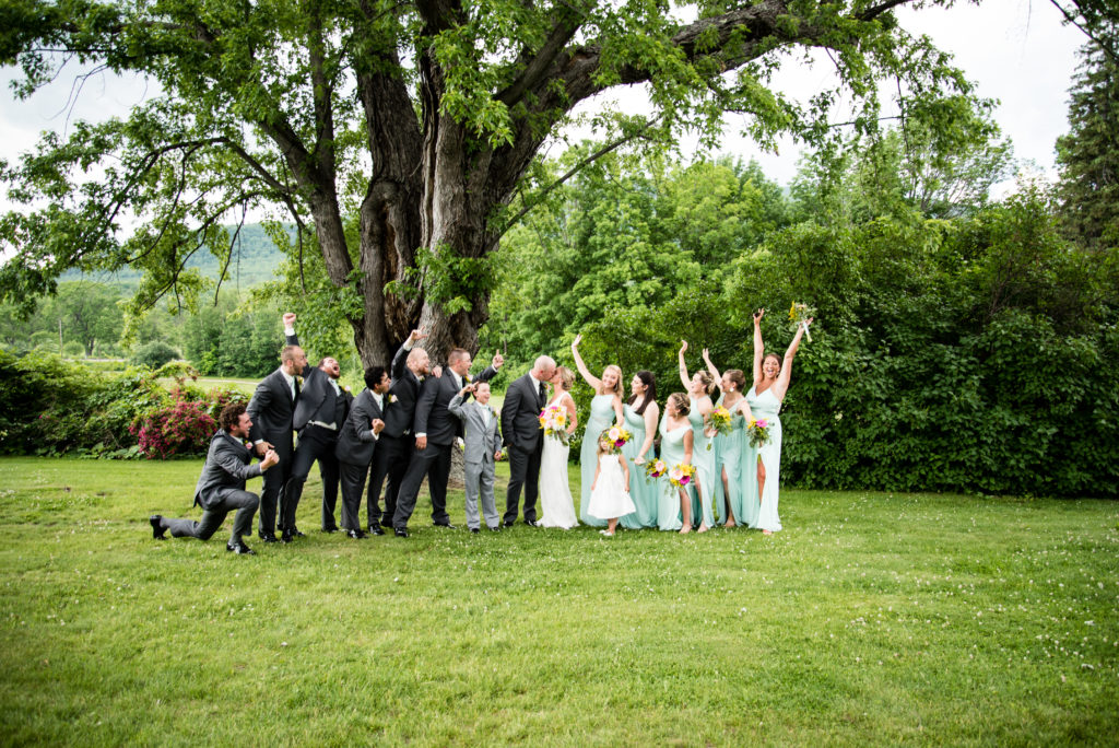 Bridal party cheering while bride and groom kiss