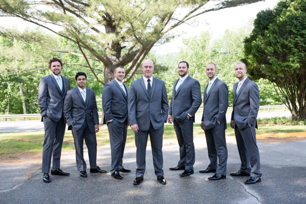 Groom with his groomsmen standing in a line with hands in pockets