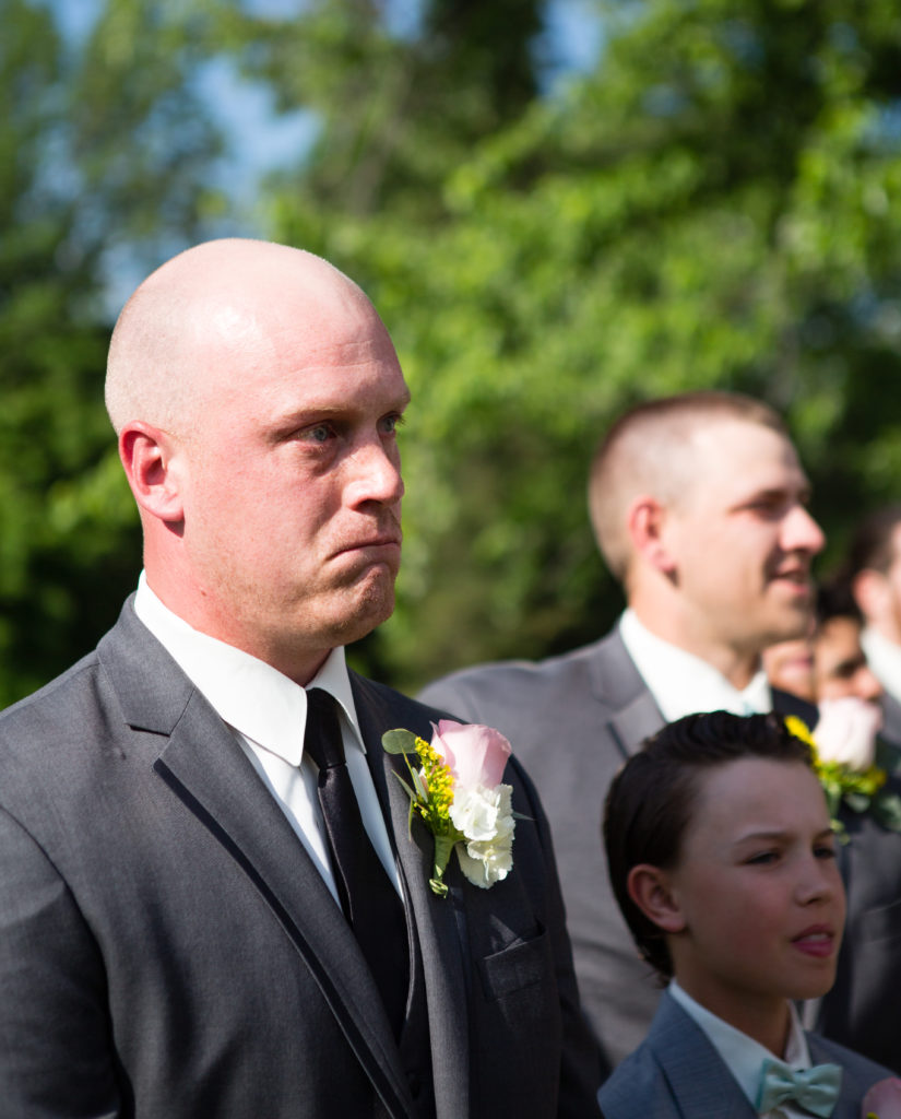 Groom watching bride walking down the aisle, tearing up