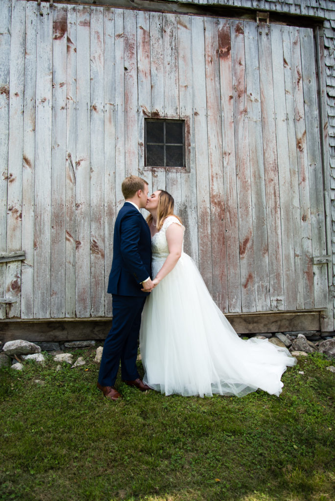 bride and groom kissing in front of the barn