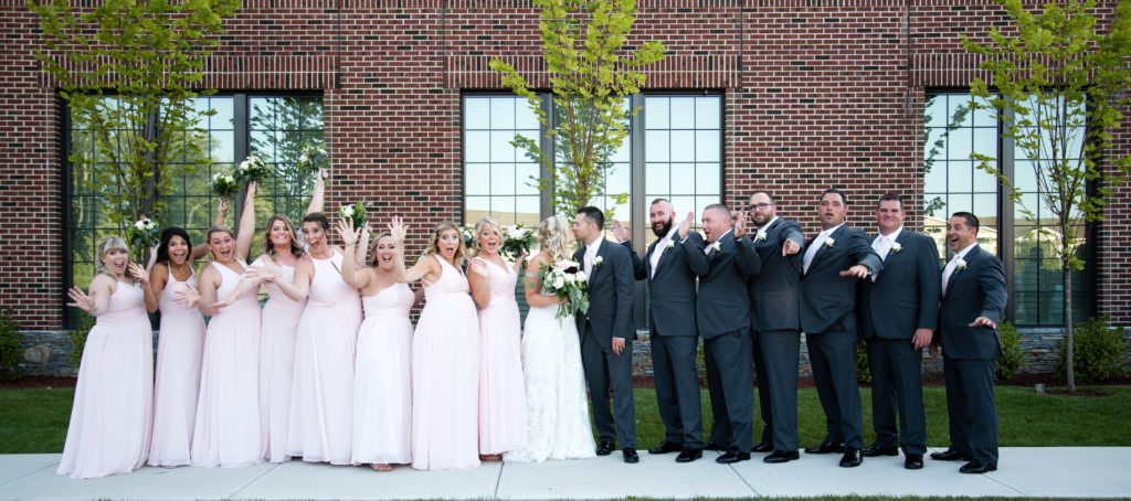 bride and groom kissing while bridal party cheers