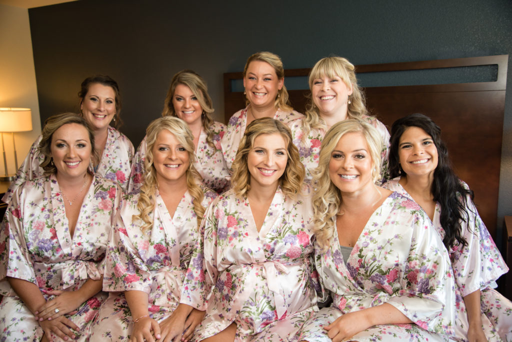 Bridesmaids with bride on bed in matching robes