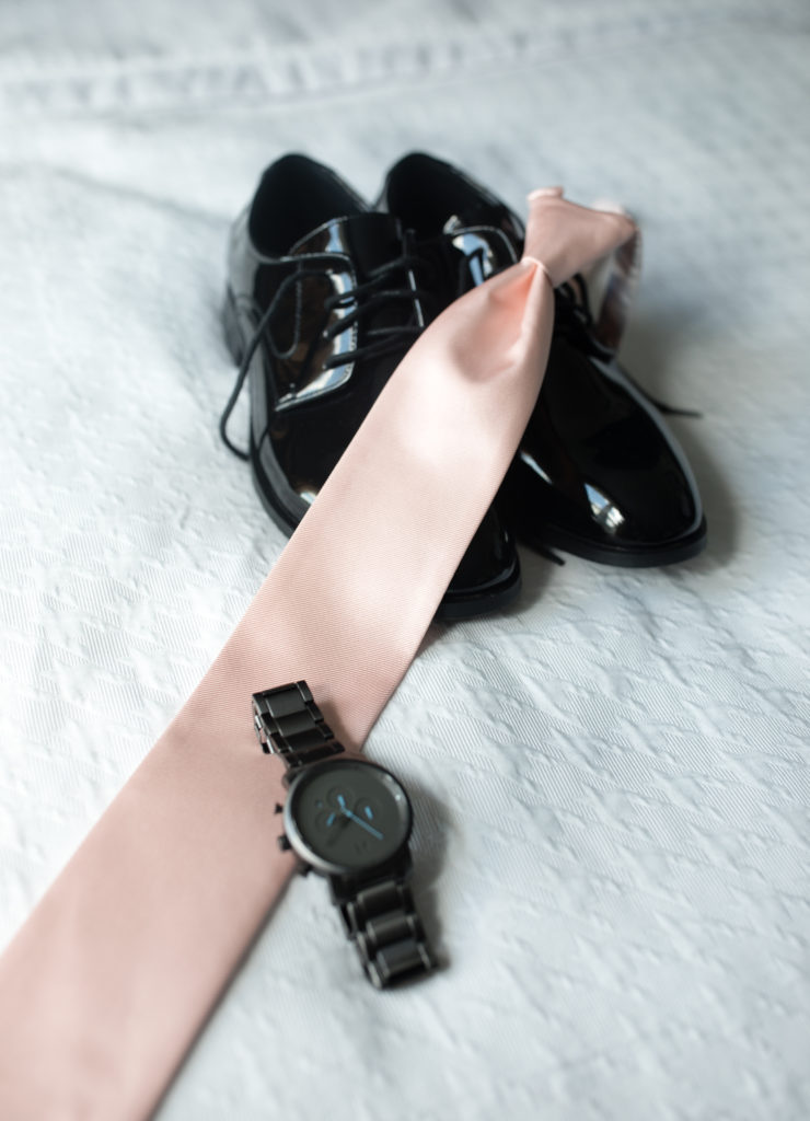 groom's shoes, watch and tie  on the bed
