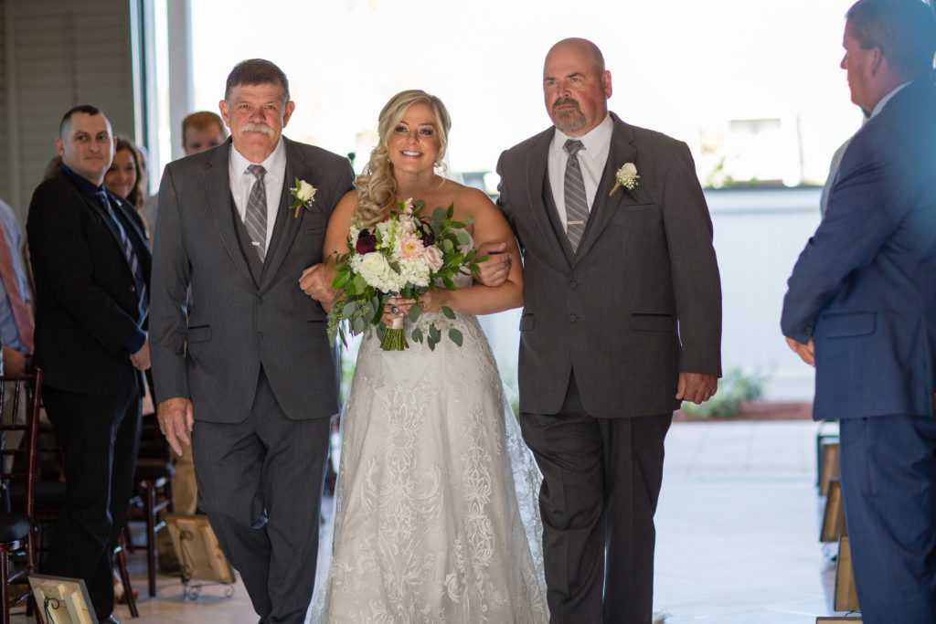 bride with her two dads walking down the aisle