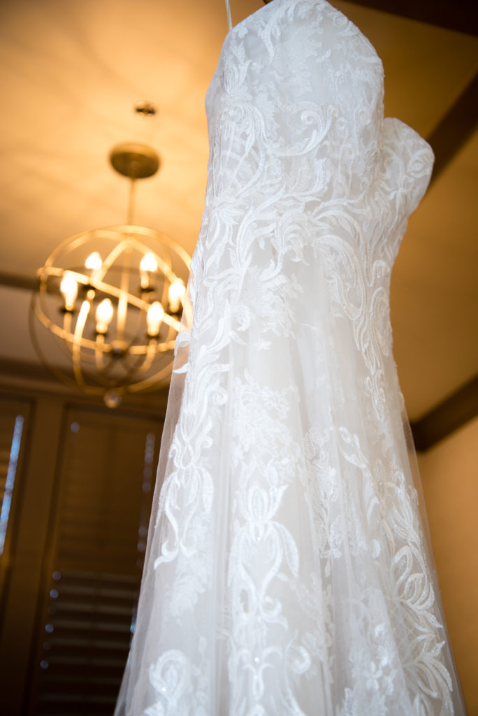 Wedding dress hanging in door with chandelier in background