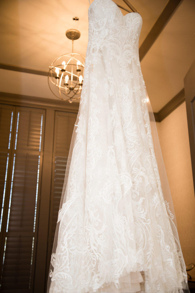wedding dress hanging in door with chandelier in background