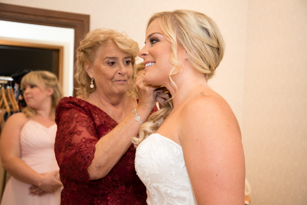 mom putting earrings on bride