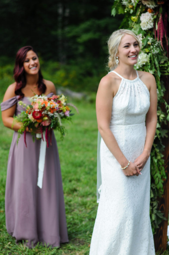 bride smiling during ceremony with maid of honor standing behind her not in focus smiling
