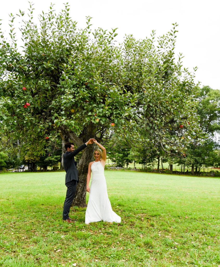 groom twirling bride under apple tree