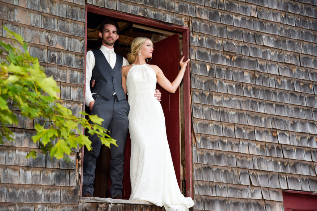 bride and groom standing in barn door 