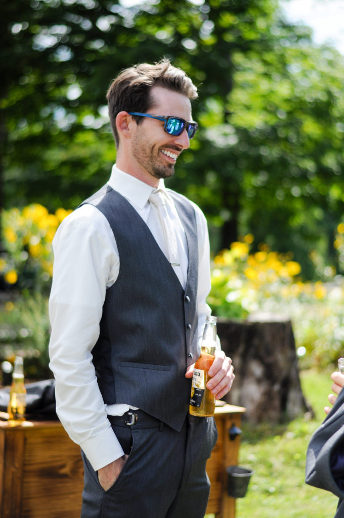 groom drinking a beer and smiling