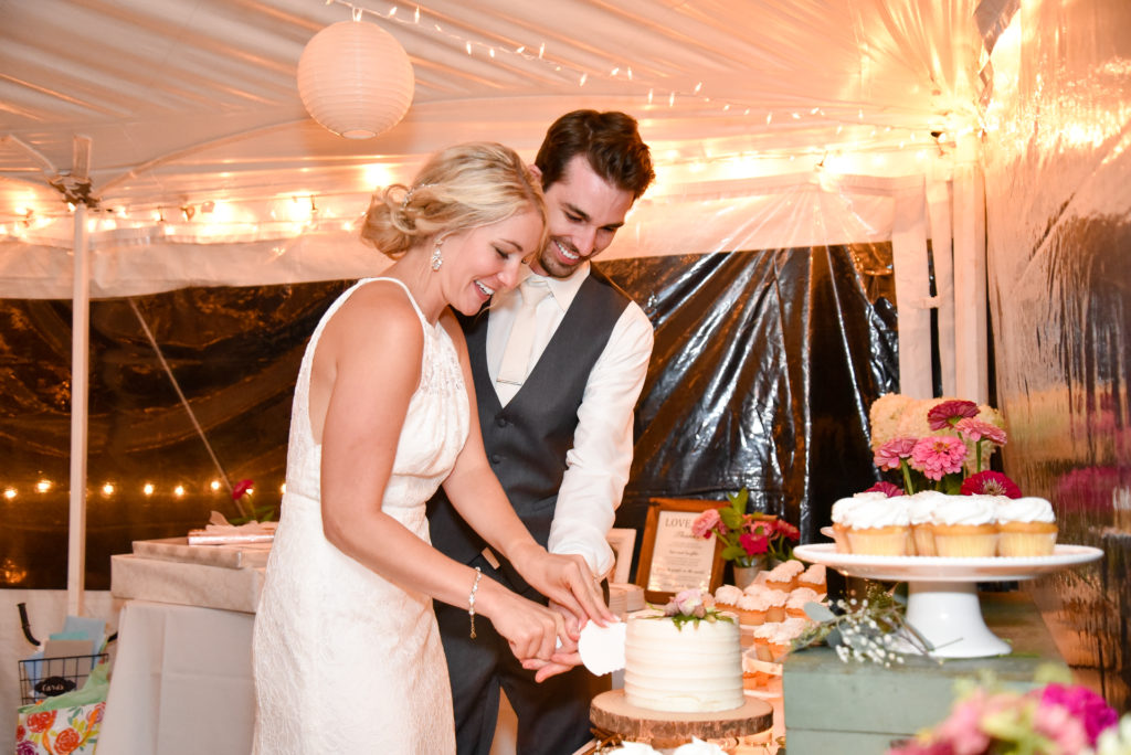 bride and groom smiling while cutting the cake