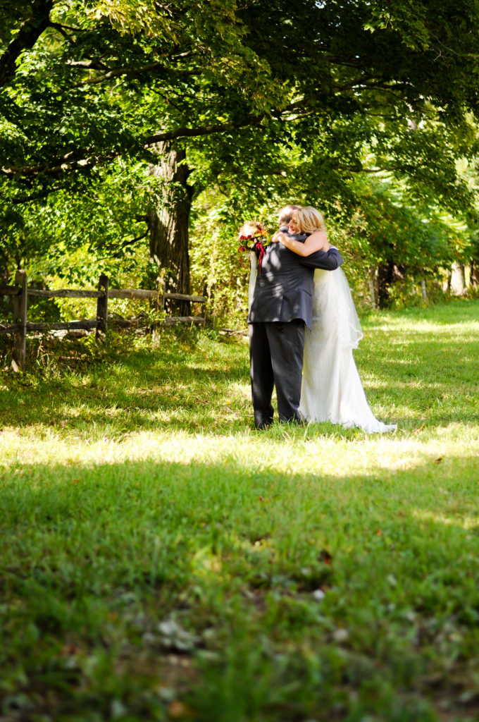 bride and her father hugging in field