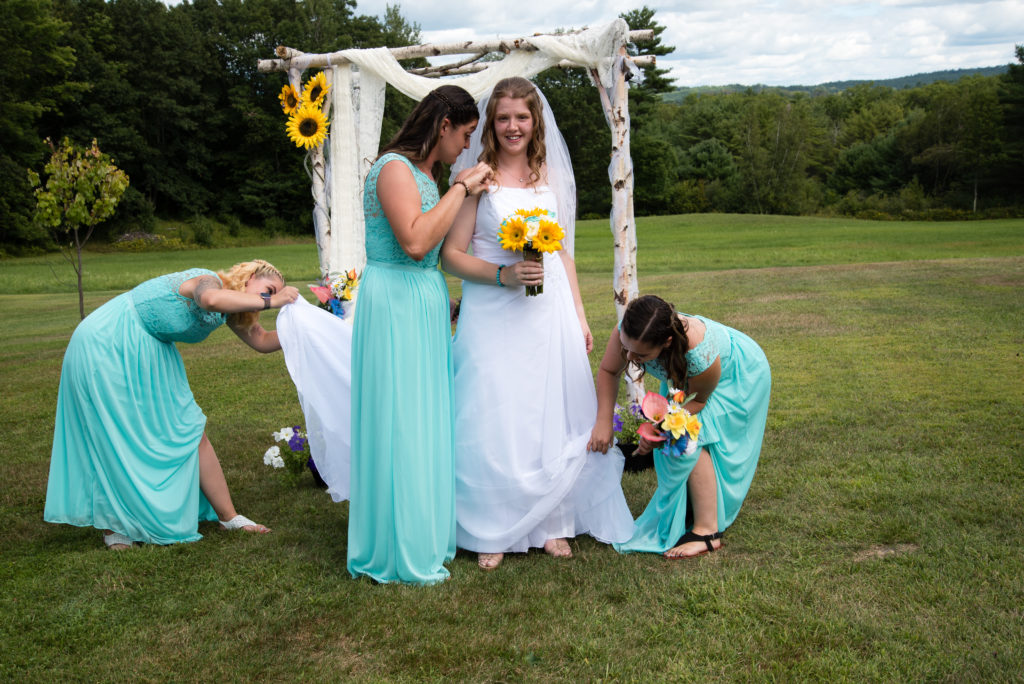 bride with silly bridesmaids looking in her dress