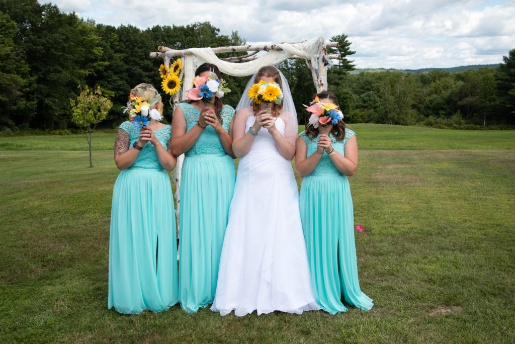 Bride and bridesmaids covering faces with bouquets