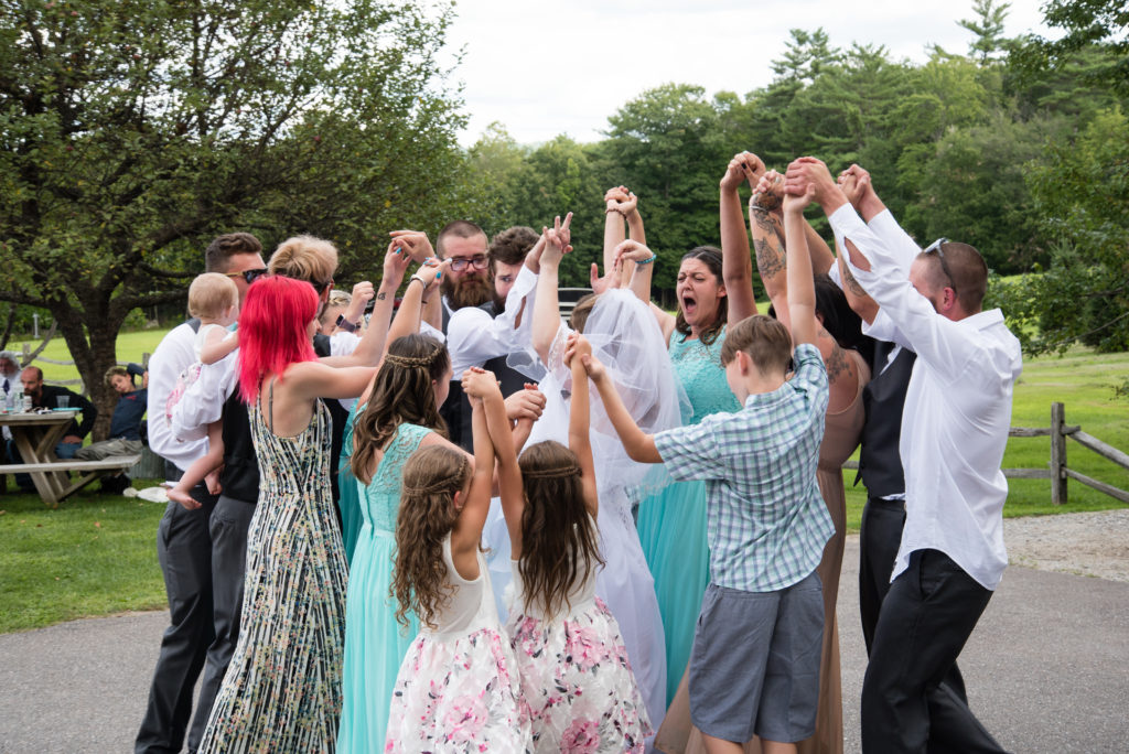 friends and family surrounding bride and groom while holding hands