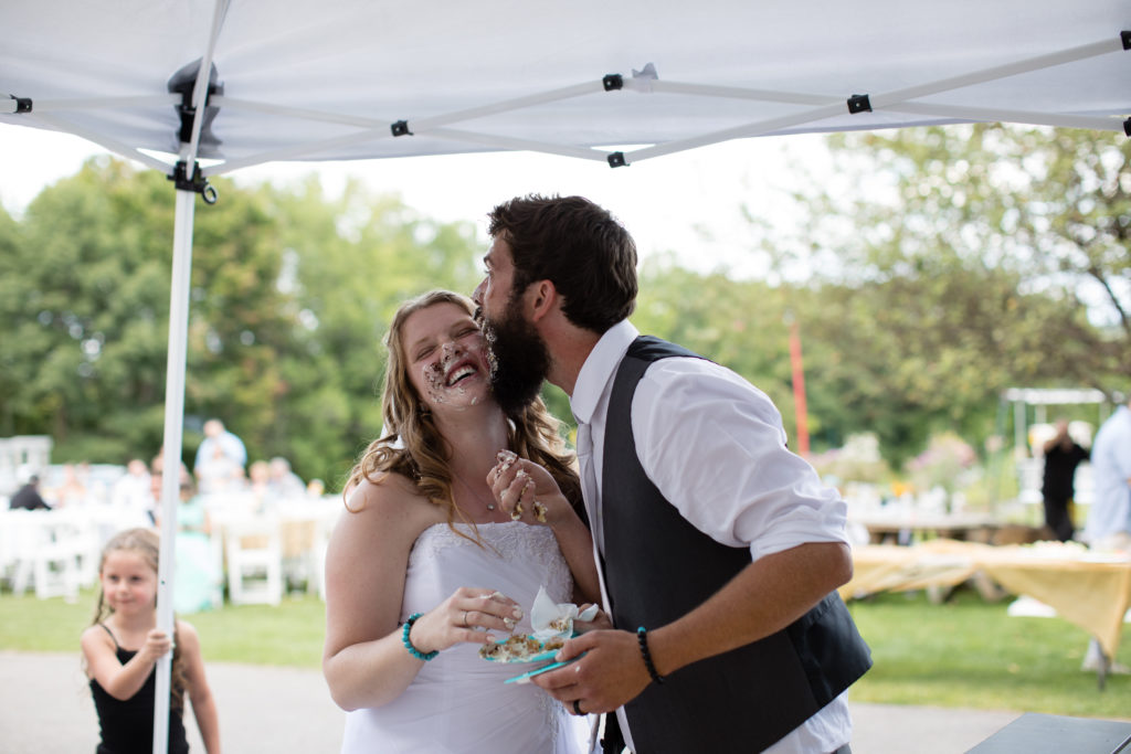groom kissing bride on cheek after cake cutting