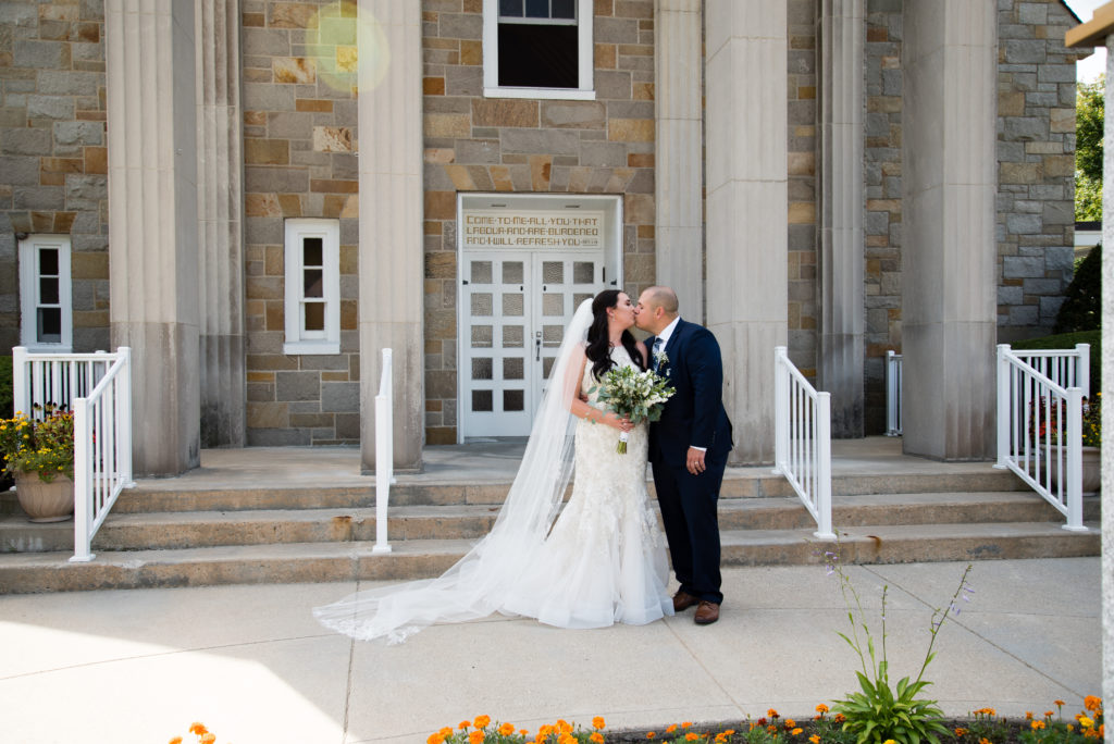 Bride and groom standing on stairs outside of church