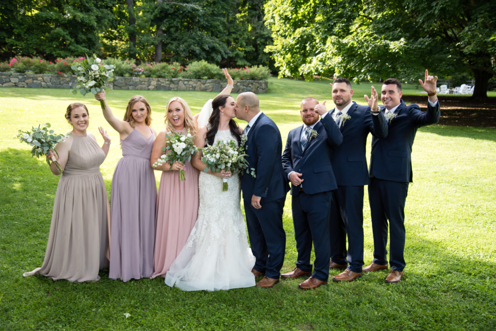 bride and groom kissing and bridal party cheering