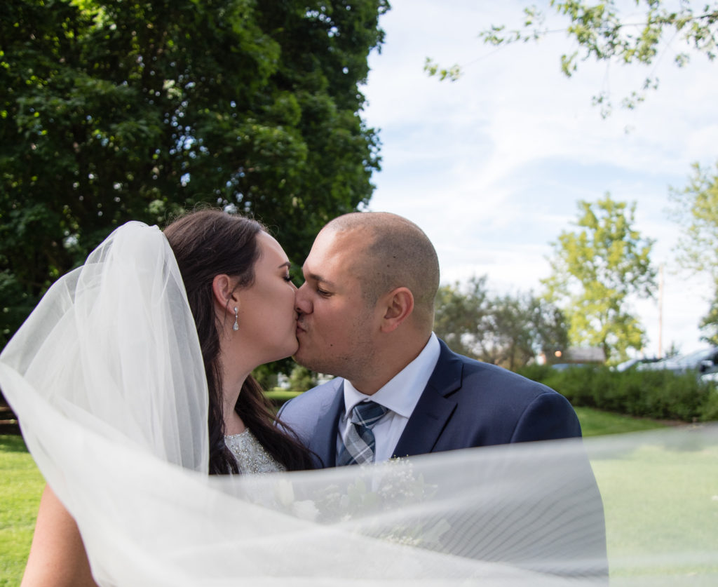 Bride and groom kissing behind the veil