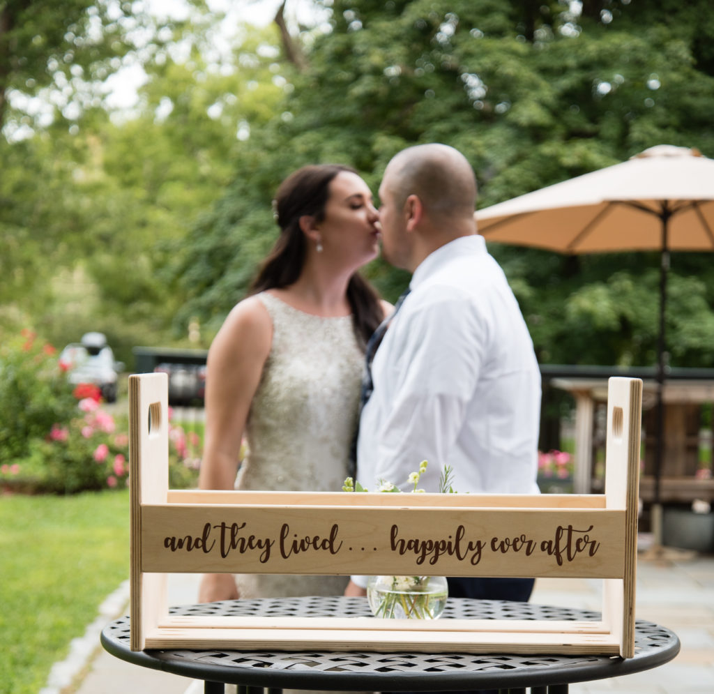 bride and groom kissing behind a sign that said "and they lived... happily ever after"