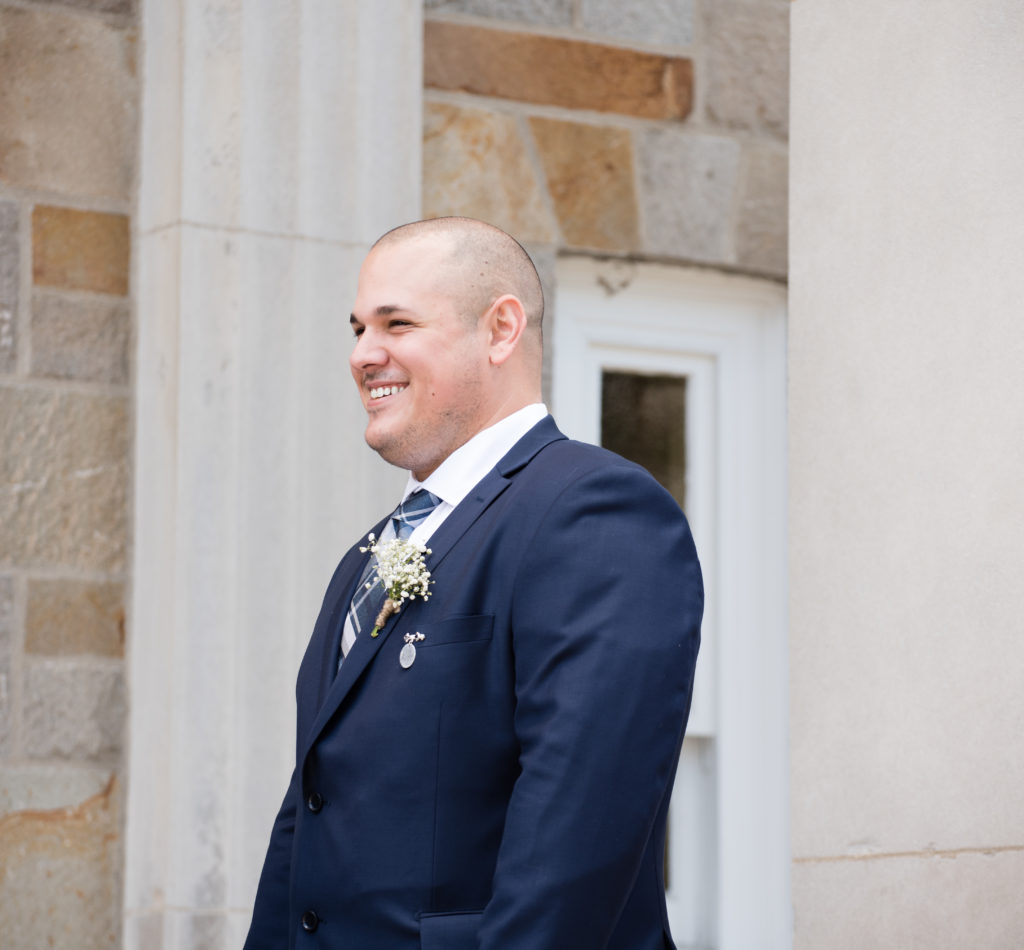 groom smiling outside of church before the ceremony