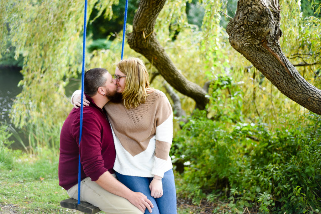 man and woman sitting on a swing looking at each other nuzzling noses