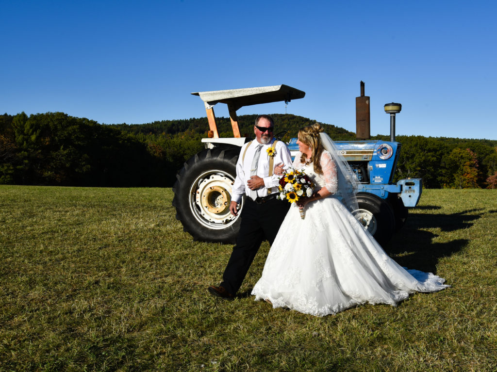 father and daughter walking down aisle with tractor in background