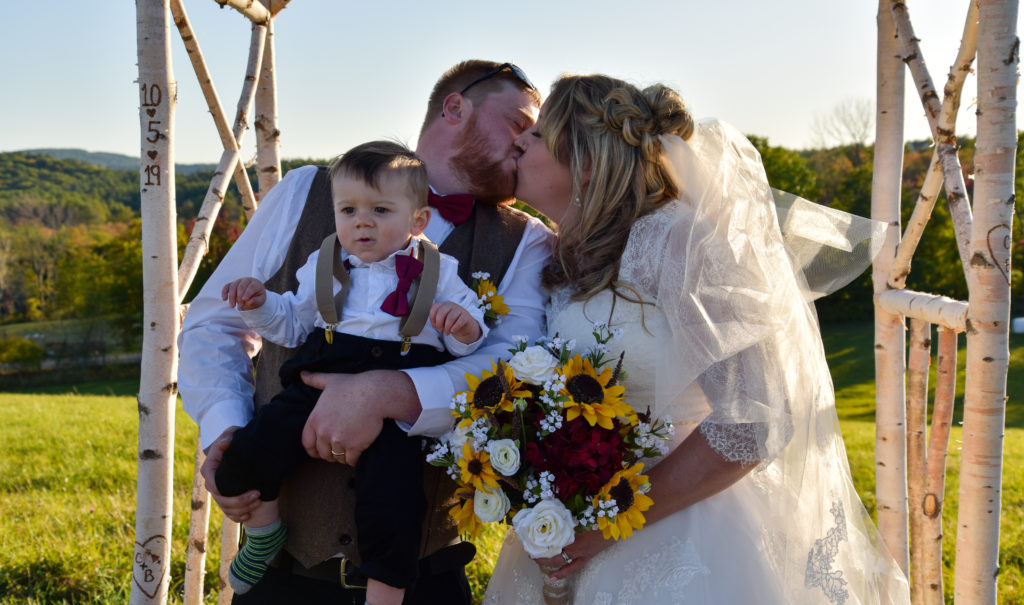 bride and groom kissing behind son 