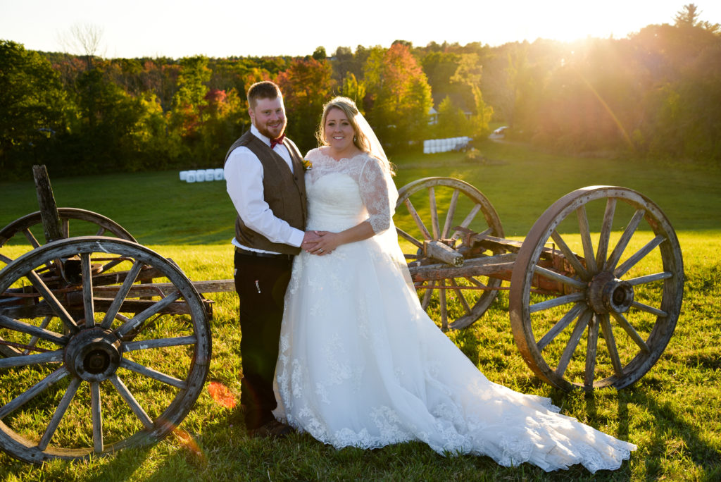 bride and groom in front of wagon in hay field