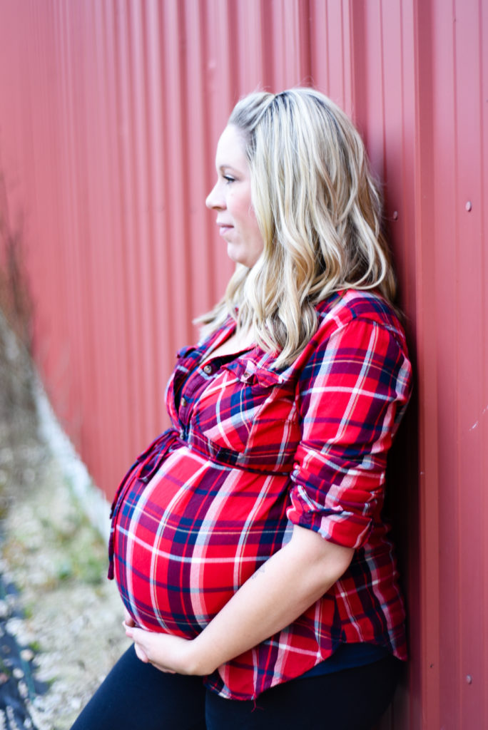 mom to be leaning against the barn - side profile of belly 