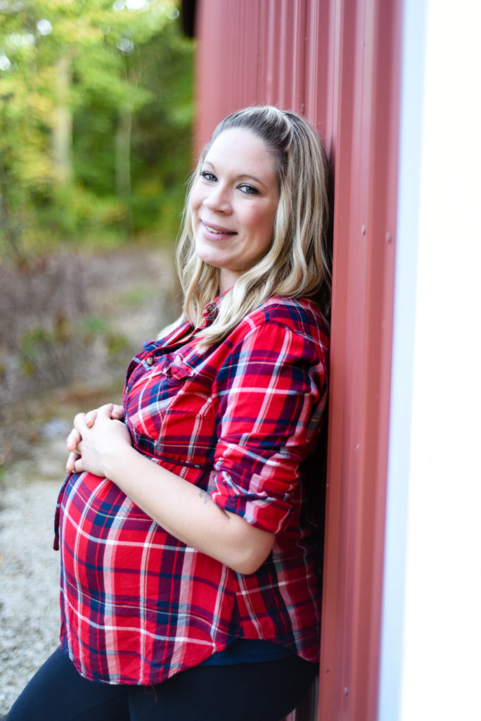 mom to be leaning against barn side profile focusing on the belly 