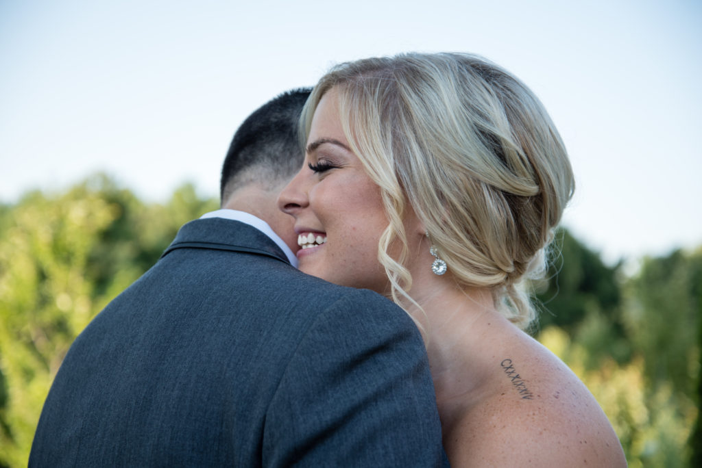 Bride and groom hugging close up on bride smiling