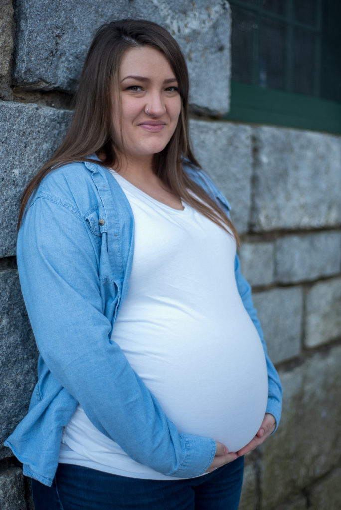 beautiful expecting mom leaning against a granite wall