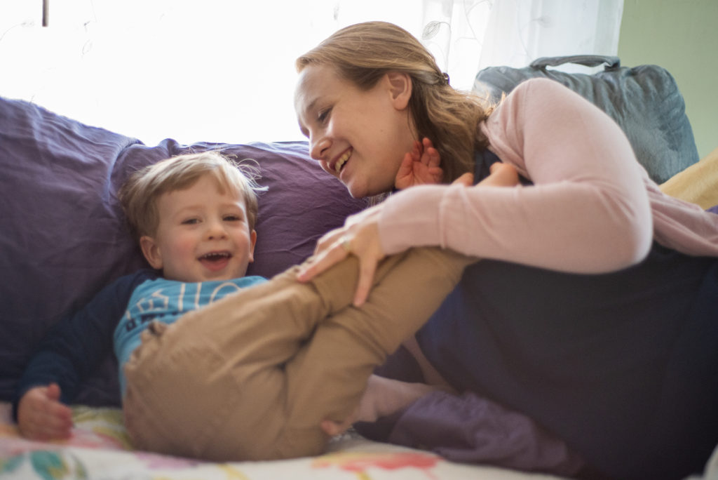 mom and son laughing on bed