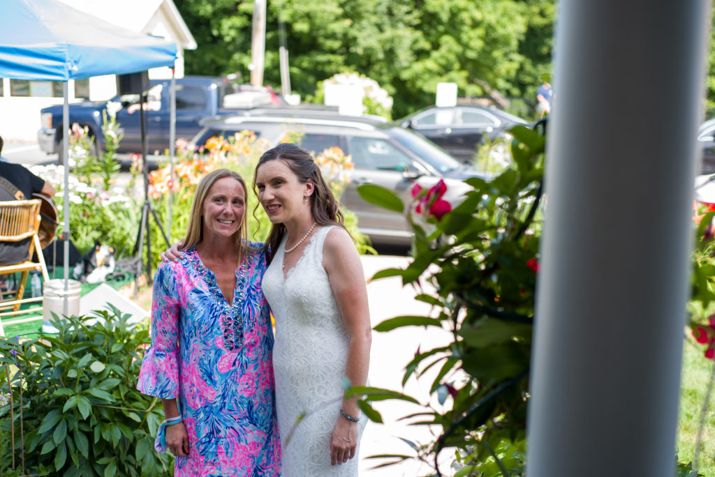 candid of bride with her best friend in front of woodstock inn brewery