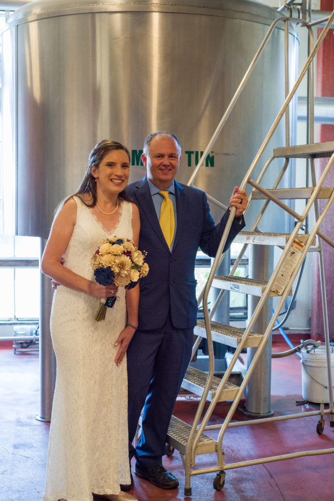 bride and groom on the ladder in front of brewery