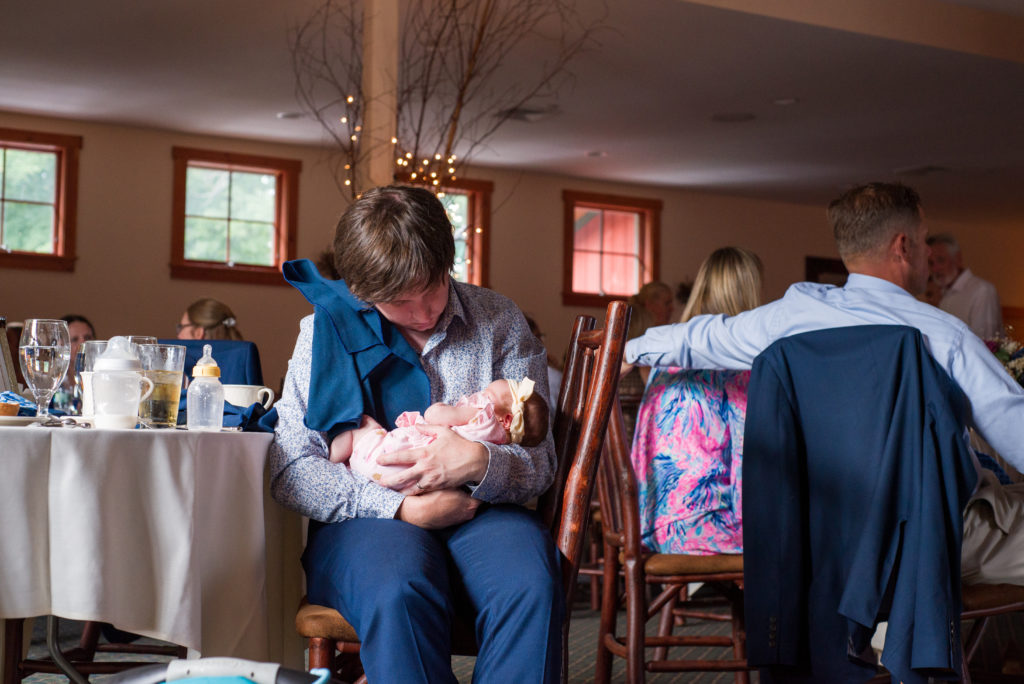 new dad holding one month old daughter at wedding 