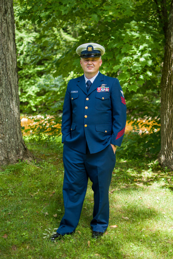 groom smiling at camera with hands in his pockets. in coast guard uniform