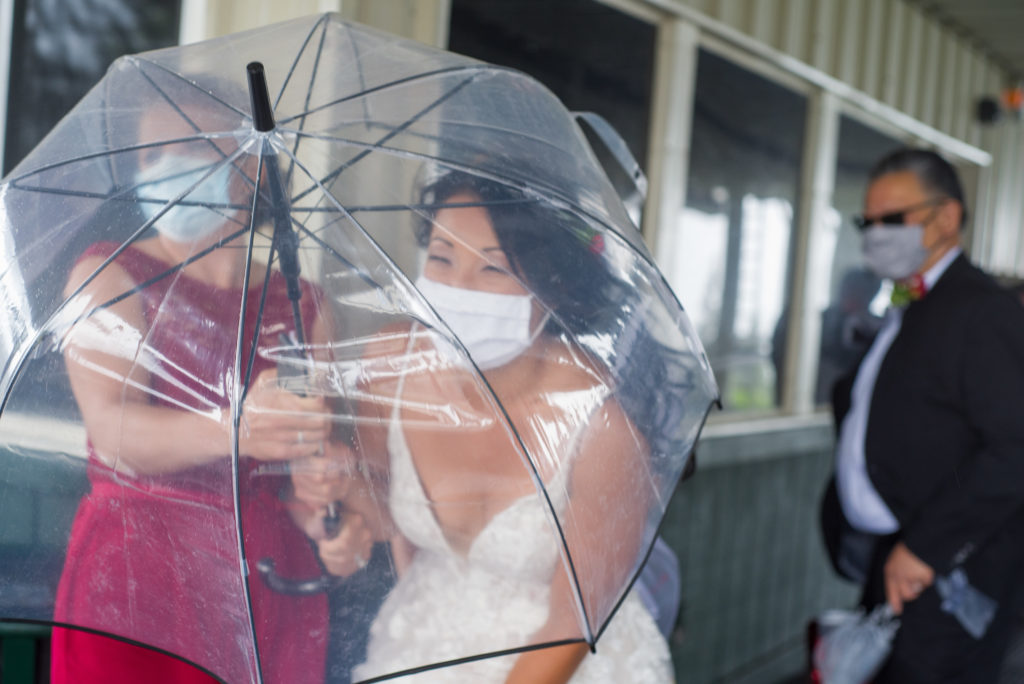 bride hiding under umbrella from gusting winds and mist