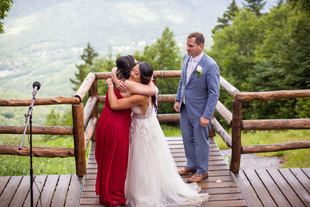 bridesmaid hugging bride after giving her speech at a mountain top wedding
