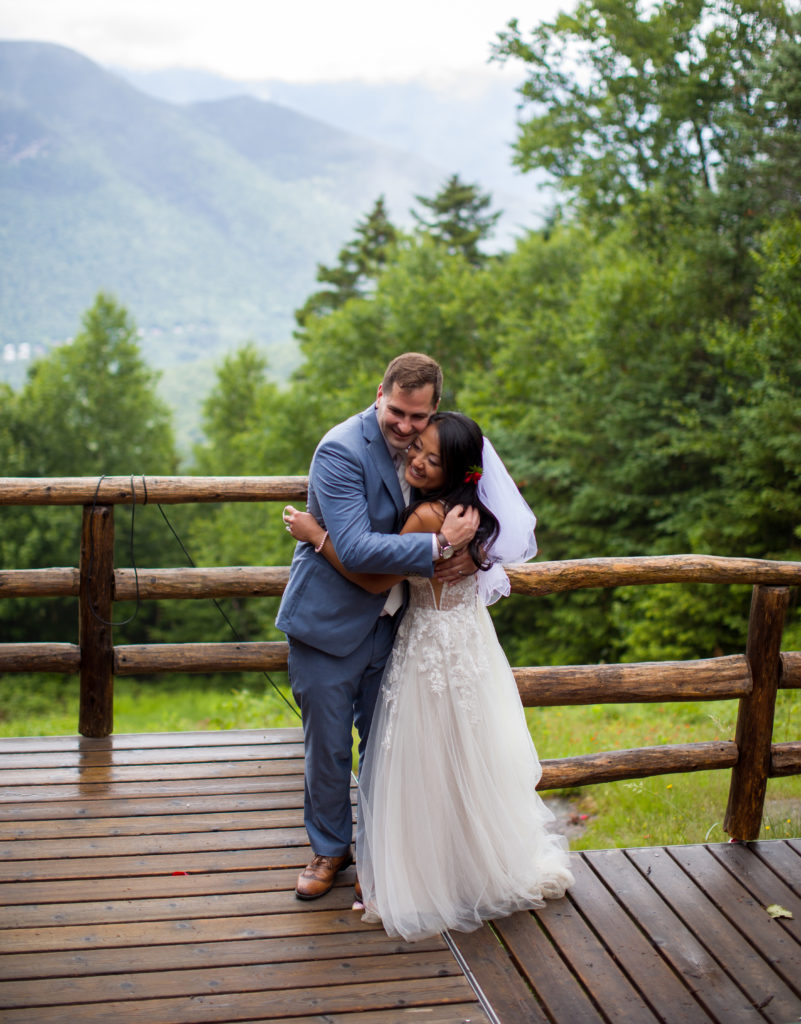 bride and groom hugging with the mountains behind them at a mountain top wedding
