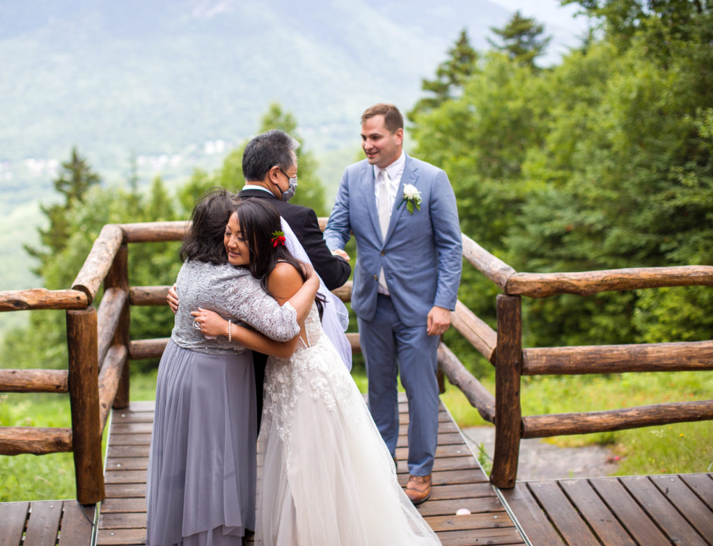 bride hugging her mom and groom shaking bride's dads hand