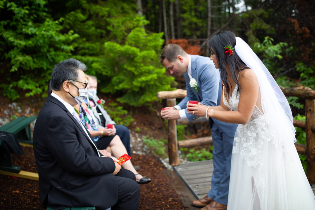 bride and groom serving bride's parents during tea ceremony at mountain top wedding