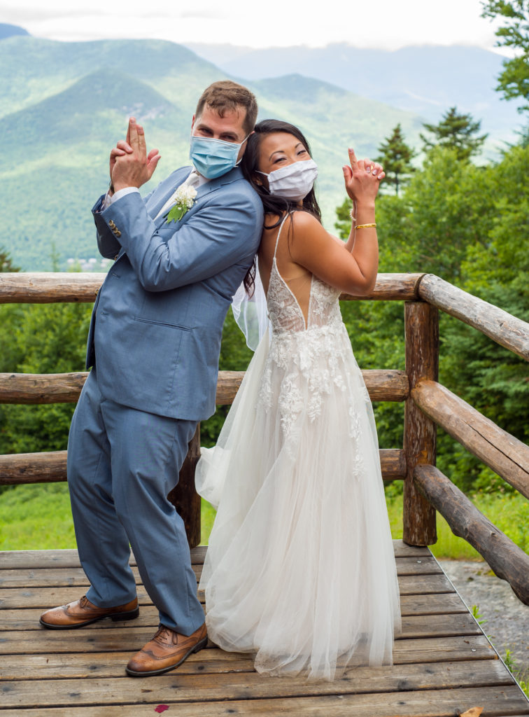 bride and groom back to back with masks on at mountain top wedding