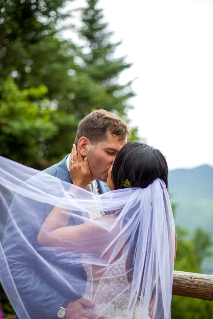 bride and groom kissing behind a veil at mountain top wedding