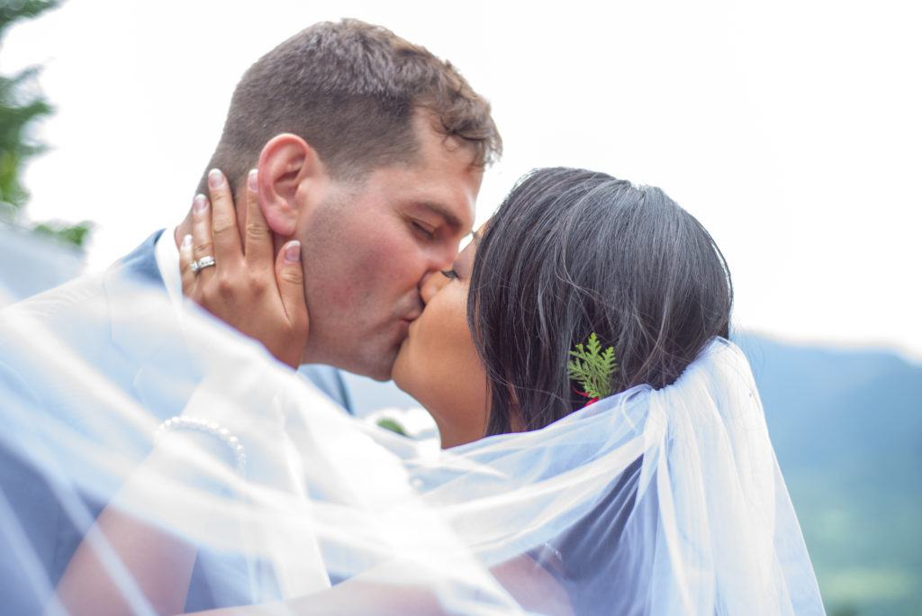 bride and groom kissing behind a veil at mountain top wedding