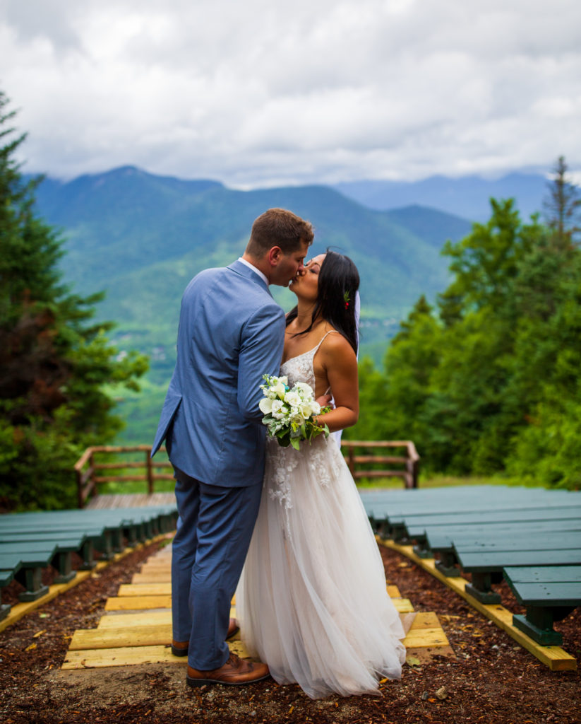 bride and groom kissing with mountains in the background at loon mountain