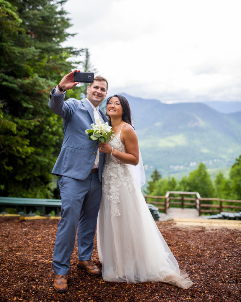bride and groom taking a selfie at mountain top ceremony